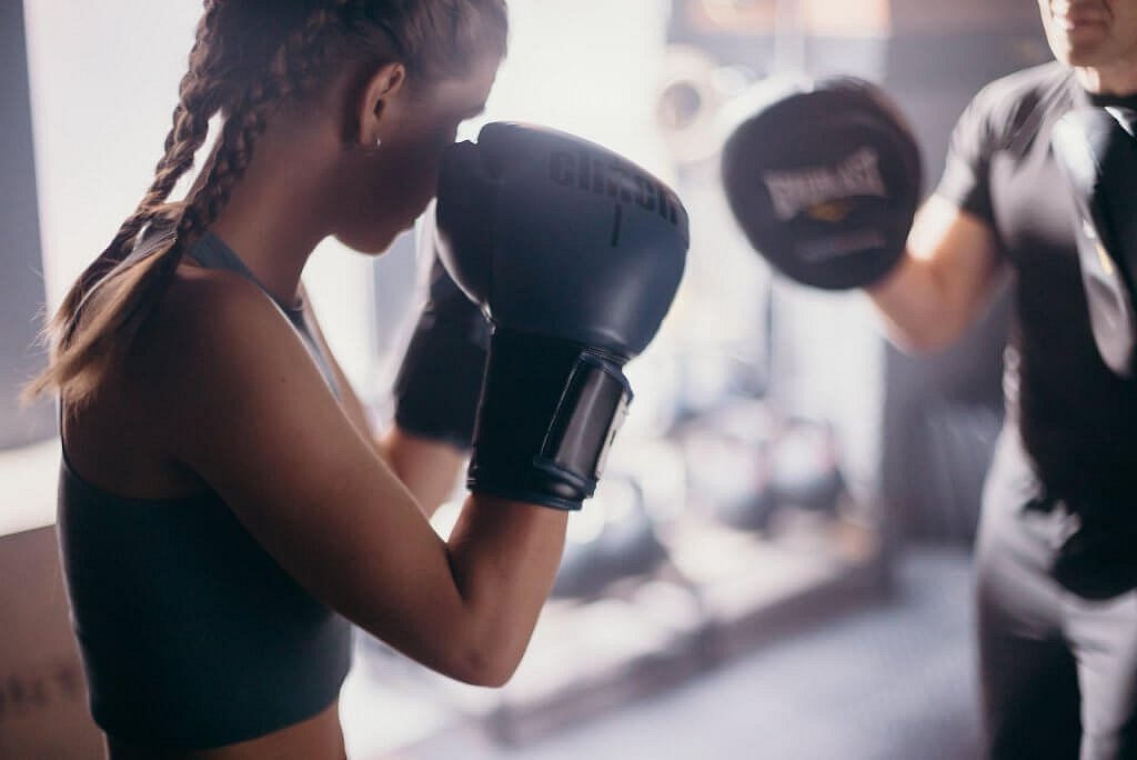 Home 22 Woman in Black Tank Top Wearing Black Boxing Gloves